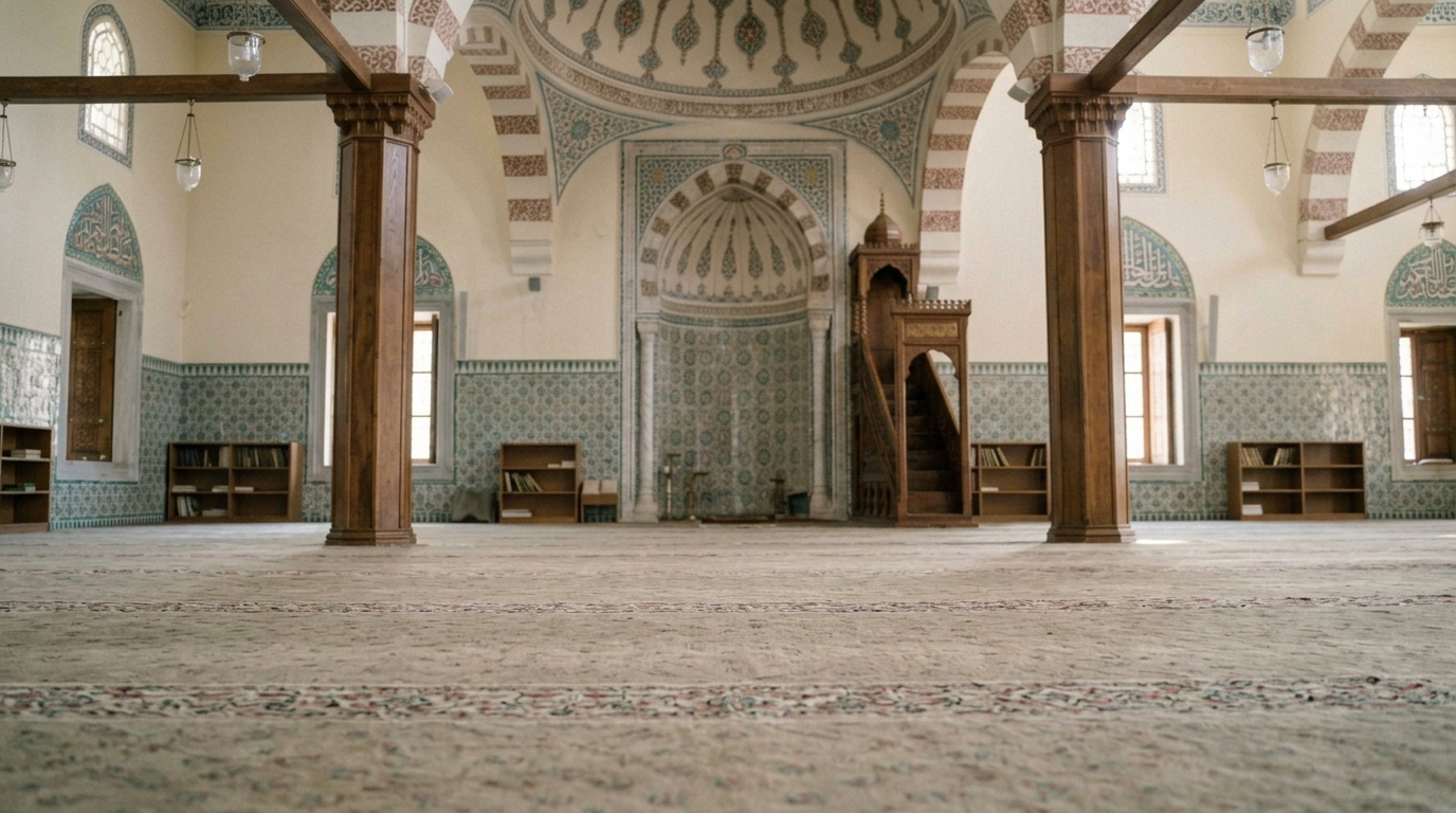 A man in a blue robe and white prayer cap prostrating on a prayer rug inside a mosque